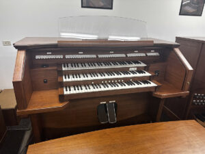 Allen ADC-720 Organ - This Allen ADC-720 is a two-channel audio instrument featuring the tab stop control console. It comes with 36 stops, three-manuals, lighted clear acrylic music rack, bench with storage area, AGO pedalboard. Two external speakers included. Price: $5,800.00.